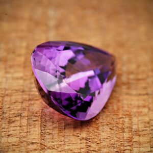 Close-up image of a sparkling purple amethyst gemstone on a textured surface.